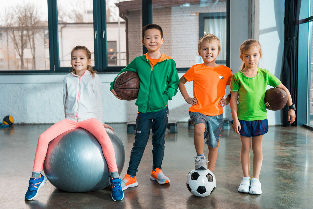 Front view of Child sitting on fitness ball next to multiethnic children with balls in gym